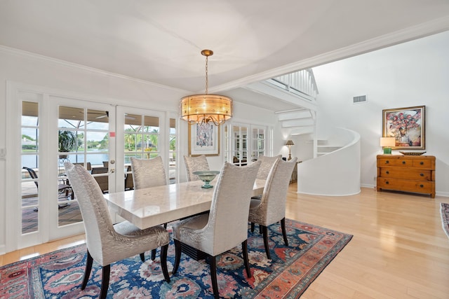 dining space featuring a chandelier, french doors, hardwood / wood-style flooring, and crown molding