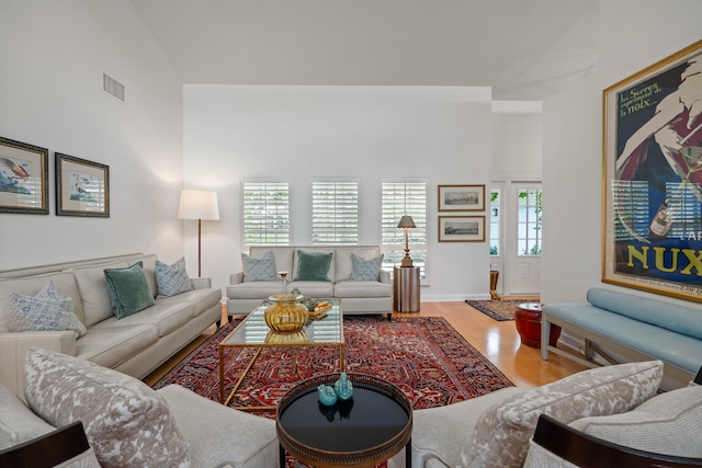 living room with plenty of natural light, high vaulted ceiling, and hardwood / wood-style floors