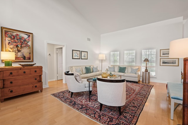 living room with light wood-type flooring and high vaulted ceiling