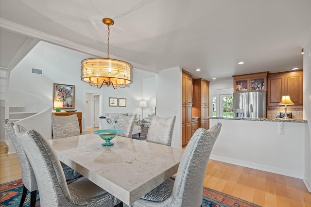 dining area with a chandelier, crown molding, and light hardwood / wood-style flooring