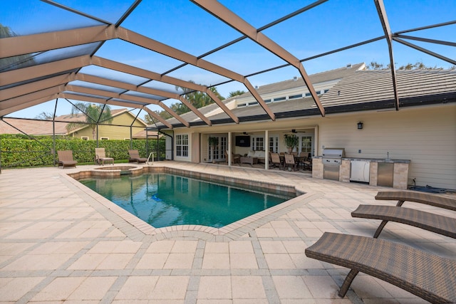 view of swimming pool with an outdoor kitchen, ceiling fan, a lanai, and a patio