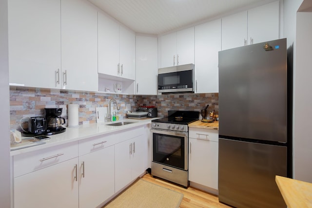 kitchen with white cabinets, stainless steel appliances, tasteful backsplash, and sink