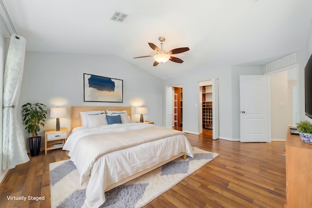 bedroom with a walk in closet, vaulted ceiling, ceiling fan, dark hardwood / wood-style floors, and a closet