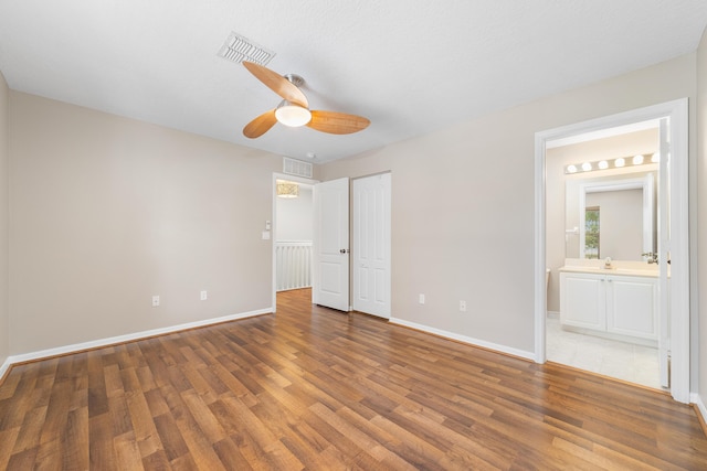 unfurnished bedroom featuring hardwood / wood-style floors, a textured ceiling, ensuite bath, and ceiling fan