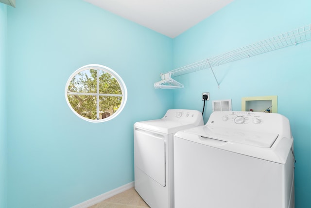 clothes washing area with washer and dryer and light tile patterned floors