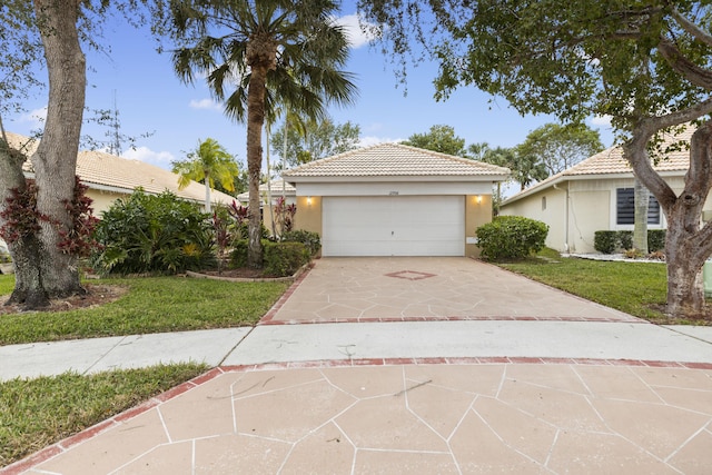 view of front of property with concrete driveway, a tile roof, a front lawn, and stucco siding