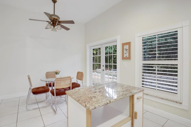 kitchen featuring ceiling fan, french doors, light stone counters, vaulted ceiling, and light tile patterned floors