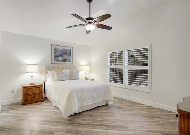 bedroom with ceiling fan, vaulted ceiling, baseboards, and wood finished floors