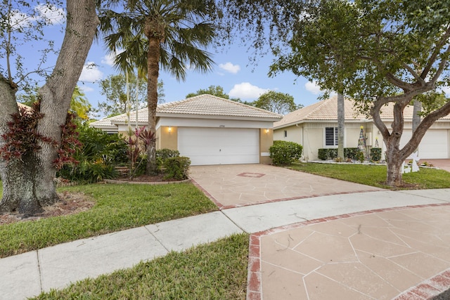 single story home with a front yard, concrete driveway, a tiled roof, and stucco siding