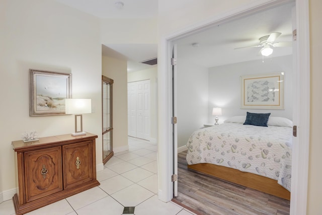 bedroom featuring a closet, light tile patterned flooring, ceiling fan, and baseboards