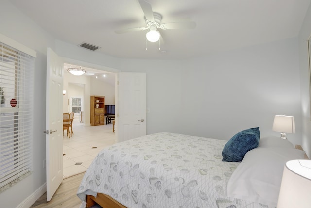 bedroom with ceiling fan, vaulted ceiling, and light wood-type flooring