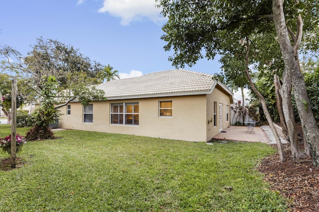 rear view of property featuring stucco siding, a tiled roof, a yard, and a patio