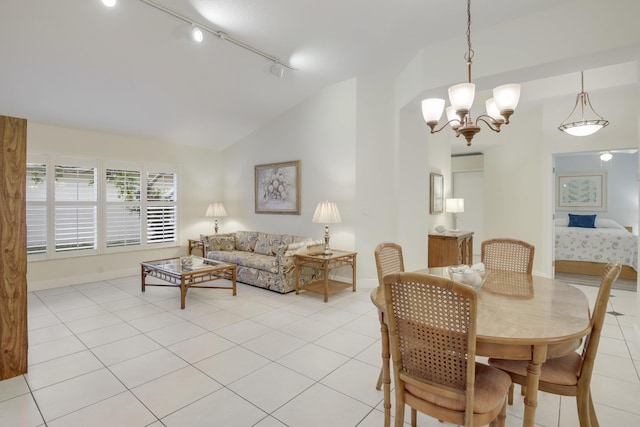 dining room with track lighting, an inviting chandelier, light tile patterned floors, and vaulted ceiling