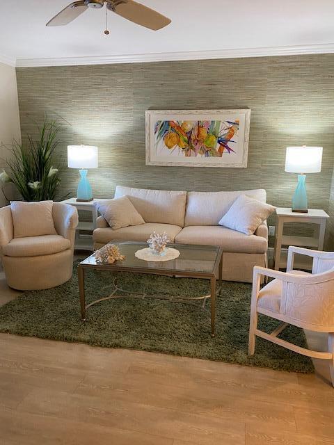 living room featuring hardwood / wood-style floors, ceiling fan, and ornamental molding