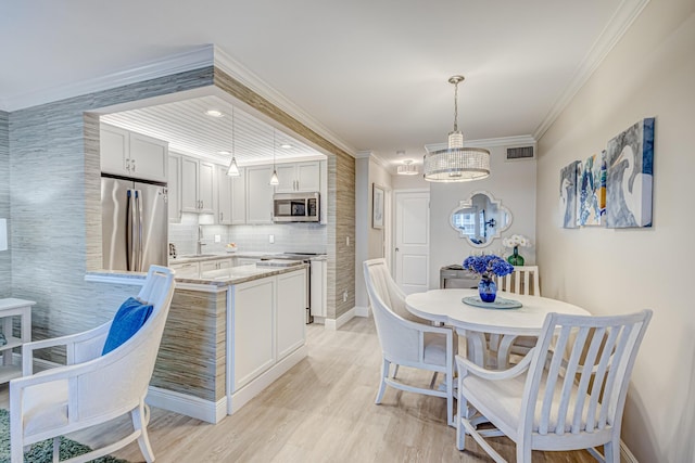 dining space with a chandelier, sink, crown molding, and light hardwood / wood-style flooring