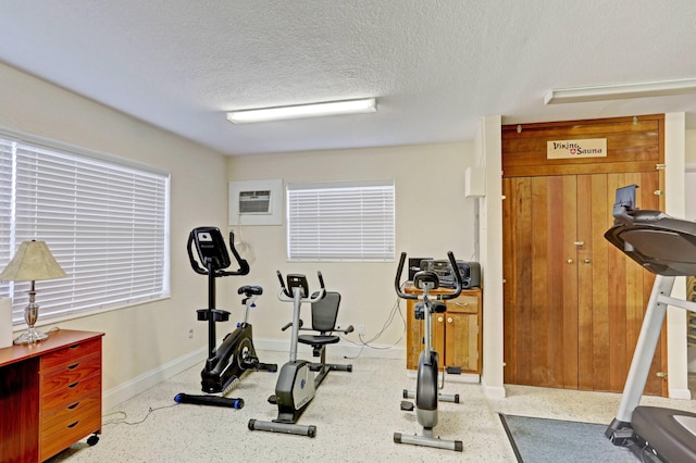 workout room featuring a textured ceiling and a wall mounted AC