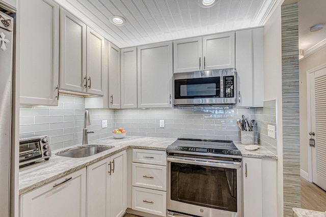 kitchen with stainless steel appliances, light stone counters, tasteful backsplash, and sink