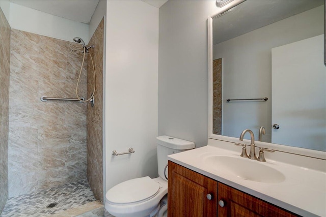 bathroom with tiled shower, vanity, and toilet