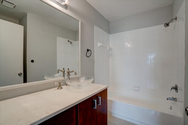 bathroom with tile patterned flooring, vanity, and tiled shower / bath