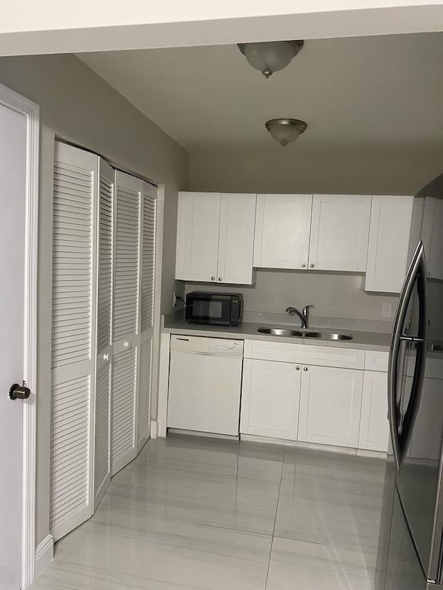 kitchen featuring stainless steel refrigerator, white cabinets, sink, and white dishwasher