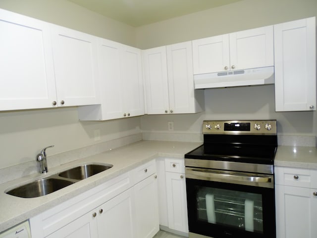 kitchen featuring electric range, light stone counters, white cabinets, and sink