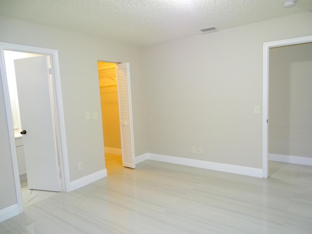 spare room featuring a textured ceiling and light hardwood / wood-style flooring