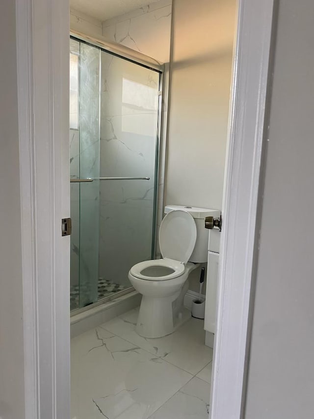 bathroom with toilet and a shower with shower door