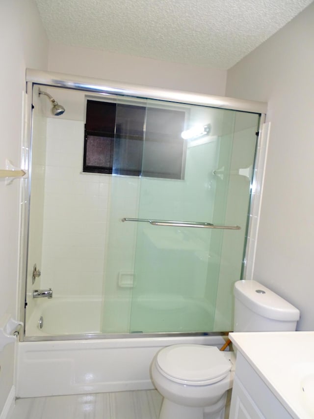 full bathroom featuring vanity, bath / shower combo with glass door, a textured ceiling, and toilet