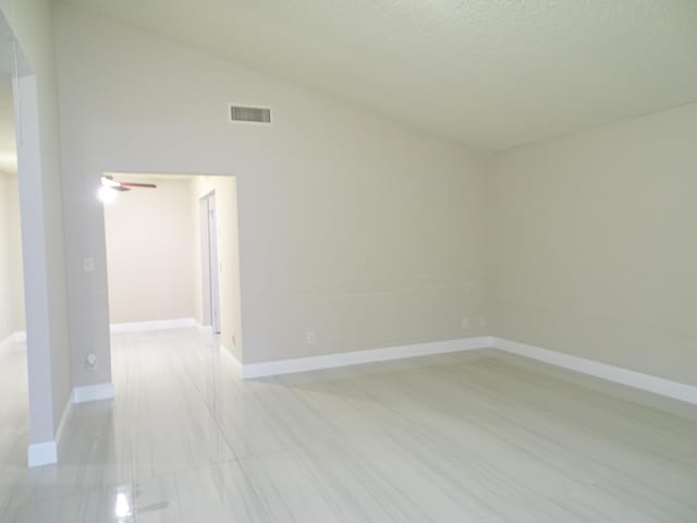 unfurnished room featuring a textured ceiling, vaulted ceiling, and ceiling fan