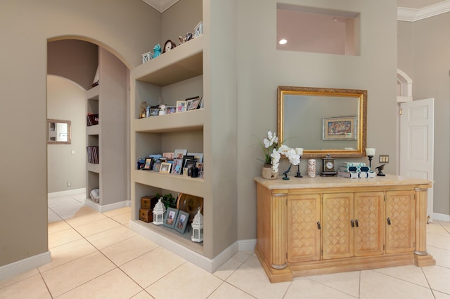 hall with light tile patterned floors, crown molding, and built in features