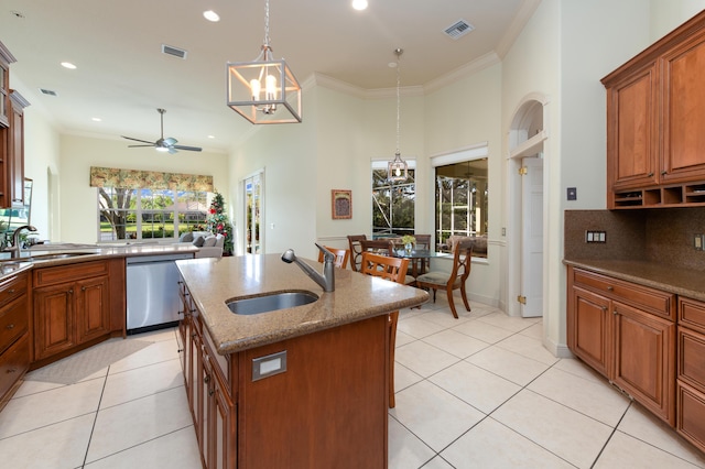 kitchen featuring stainless steel dishwasher, ceiling fan with notable chandelier, a center island with sink, and sink