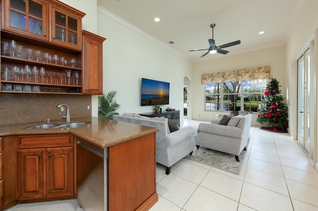 living room with light tile patterned floors, crown molding, indoor wet bar, and ceiling fan