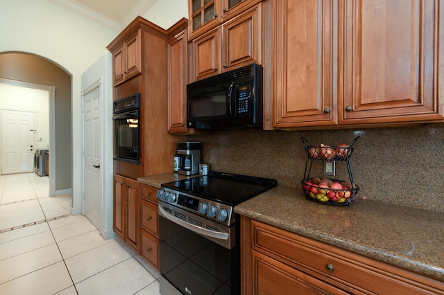 kitchen featuring dark stone countertops, decorative backsplash, ornamental molding, light tile patterned floors, and black appliances