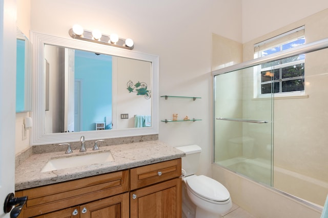 full bathroom with vanity, bath / shower combo with glass door, and toilet