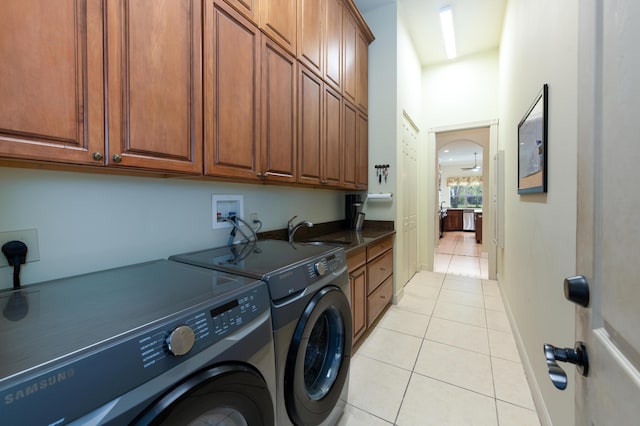 washroom featuring independent washer and dryer, sink, cabinets, and light tile patterned flooring