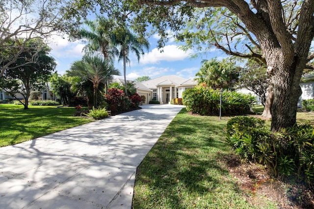 18640 SE River Ridge Rd, Jupiter, FL 33469 - view of front of house featuring an attached garage, driveway, and a front lawn