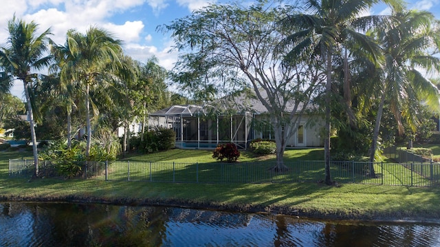 rear view of house featuring a water view, a yard, and glass enclosure