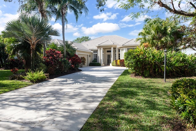 18640 SE River Ridge Rd, Jupiter, FL 33469 - view of front of house featuring an attached garage, driveway, a front lawn, stucco siding, and a tile roof
