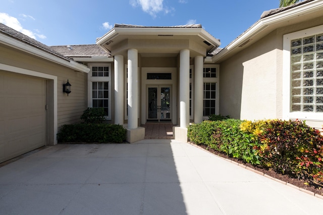 18640 SE River Ridge Rd, Jupiter, FL 33469 - property entrance featuring french doors, stucco siding, a garage, and concrete driveway
