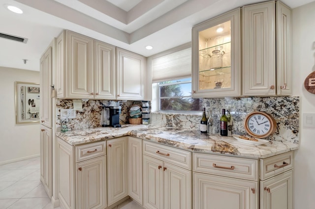 kitchen featuring backsplash, light stone counters, and cream cabinets