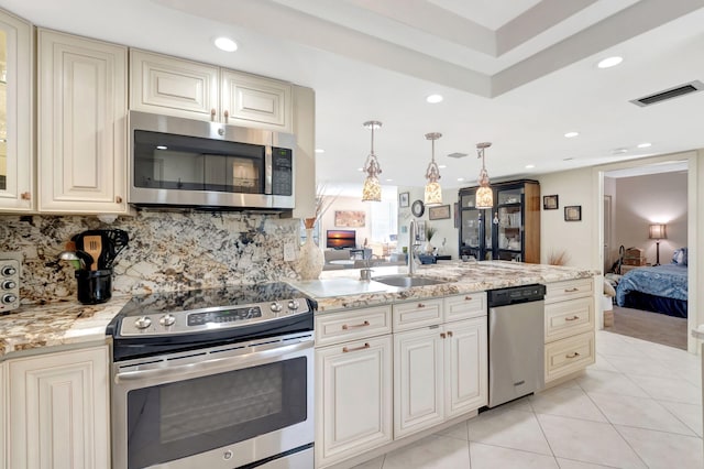 kitchen featuring sink, pendant lighting, cream cabinetry, light tile patterned flooring, and appliances with stainless steel finishes