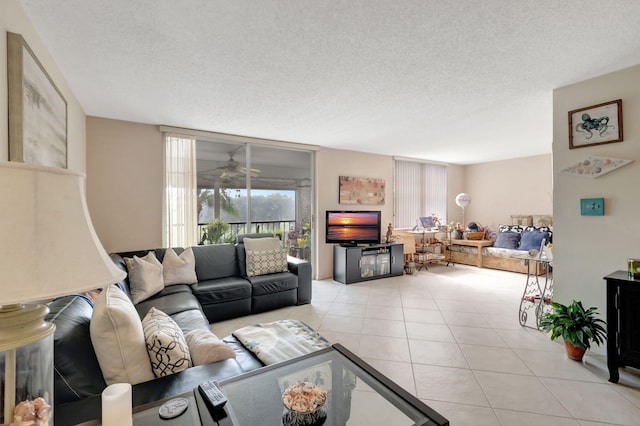 living room featuring ceiling fan, light tile patterned floors, and a textured ceiling