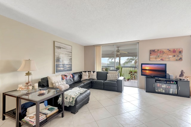 living room with ceiling fan, light tile patterned flooring, and a textured ceiling