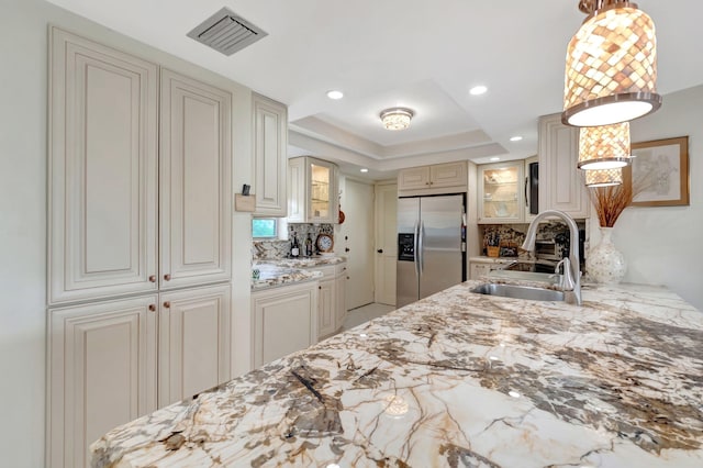 kitchen featuring sink, hanging light fixtures, tasteful backsplash, light stone counters, and appliances with stainless steel finishes