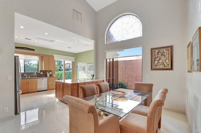 dining room with light tile patterned floors and high vaulted ceiling