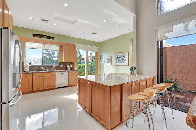 kitchen with sink, backsplash, stainless steel appliances, and light tile patterned flooring