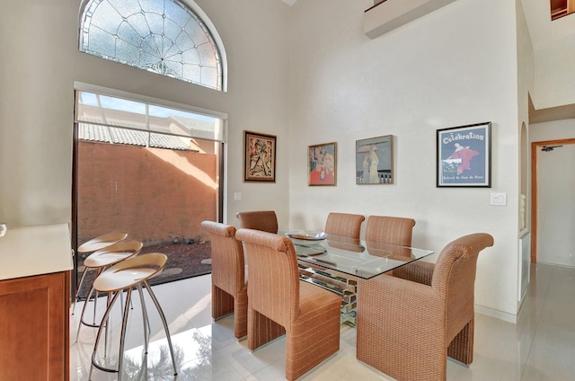 dining room with a towering ceiling and light tile patterned floors