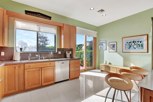 kitchen with light tile patterned flooring, tasteful backsplash, stainless steel dishwasher, and sink