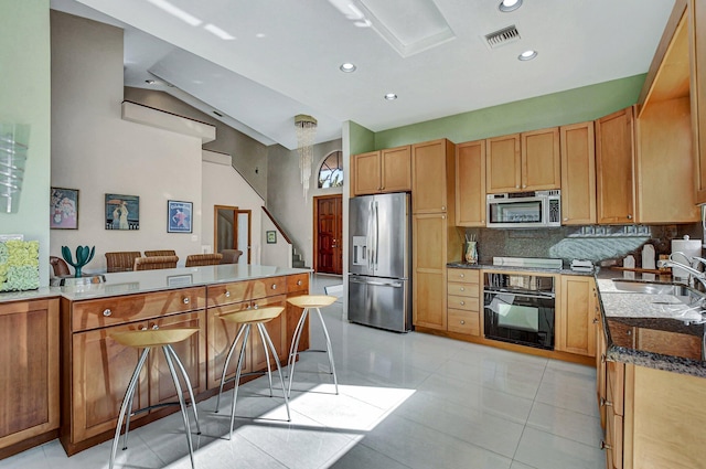 kitchen with sink, stainless steel appliances, a kitchen bar, decorative backsplash, and light tile patterned floors