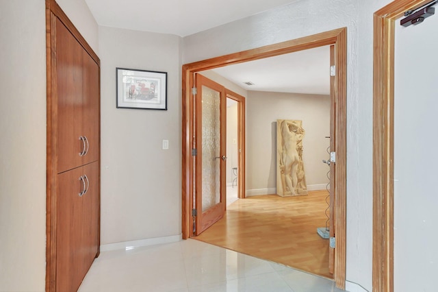 hall with light wood-type flooring and french doors